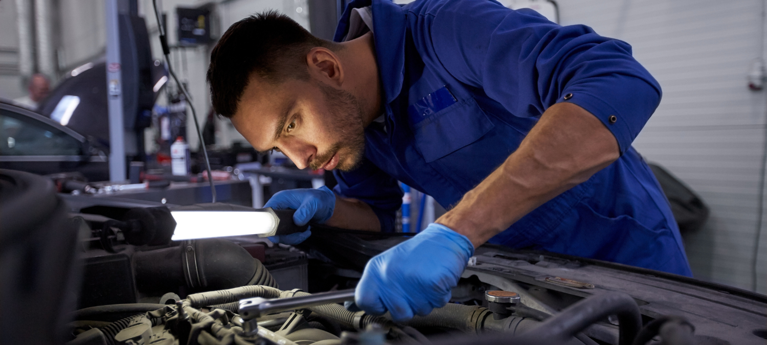 A Newgate auto mechanics student working on a car in the shop