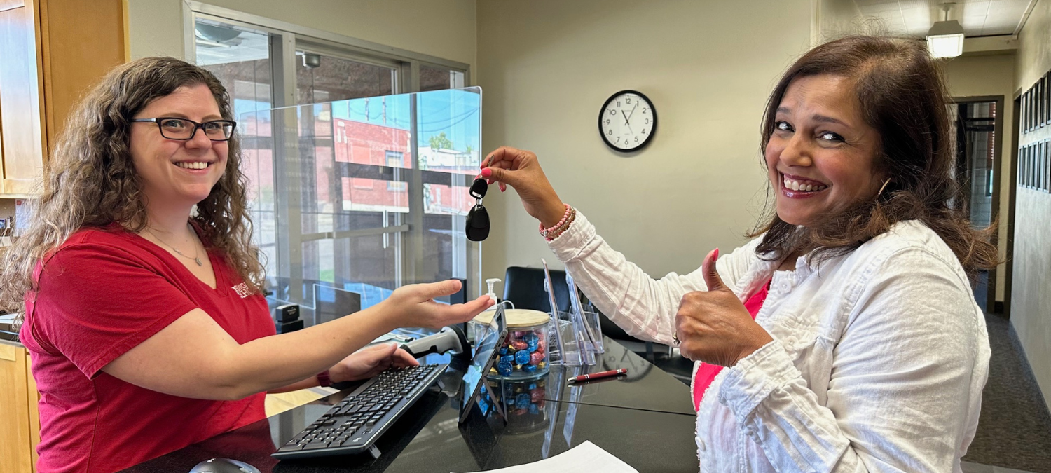 A Newgate School donation specialist and a donor exchanging car keys at the front desk